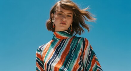 Young caucasian female in striped dress against clear blue sky