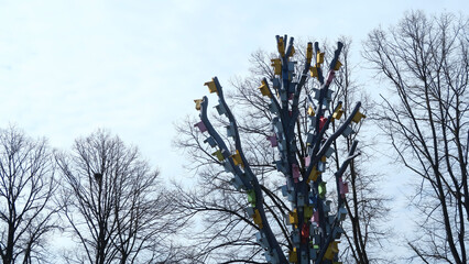 Riga, Latvia. Artistic installation with wooden bird-houses on wood branches as an artwork in a town landscape design. Many colorful wooden birdhouses on a tree foliage background.