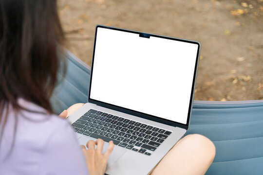 Woman working on laptop outdoors with blank screen - Powered by Adobe