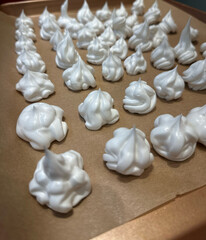 Fluffy meringue drops on baking tray displayed for culinary delights - concept of bakery, cookware, food styling