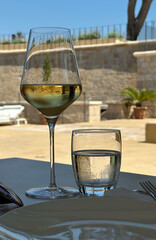 Glass of white wine and water on table outdoors - refreshing summer drink concept of restaurant, winery, patio dining
