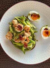 Gourmet shrimp and avocado toast with soft-boiled eggs and pesto on white plate – concept of cafe, restaurant, brunch spot