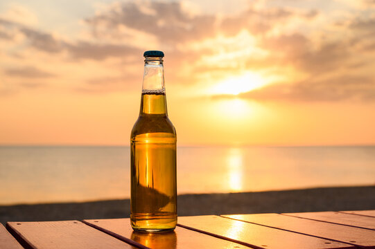 A bottle of lager beer on the seashore. Sunset on the beach and a bottle of beer.