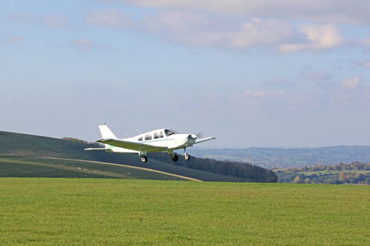 Light airplane taking off from a grass runway - Powered by Adobe