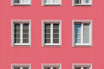 Fototapeta premium Pink Apartment Facade with Symmetrical White Windows