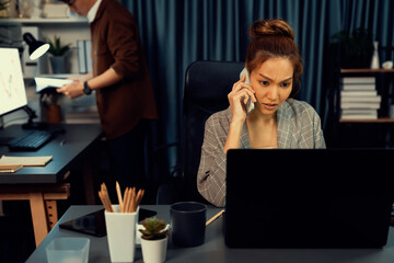 Businesswoman calling with customers to make new project job at modern office while coworker checking paperwork folder of business plan to database report meeting at over late night time. Infobahn.
