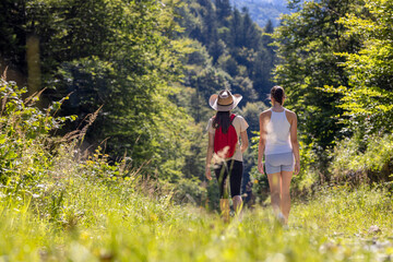 Obraz premium Two young girls on a nature trip during the holidays. Walking, hiking in the forest. Healthy lifestyle, cardio, fitness