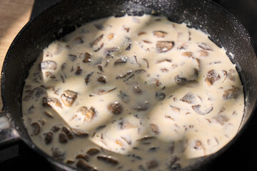 A skillet filled with creamy mushroom sauce slowly simmers on the stove