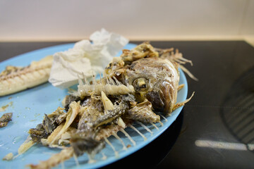 Dorado fish is presented on a blue plate, showcasing only its bones and remnants after being eaten