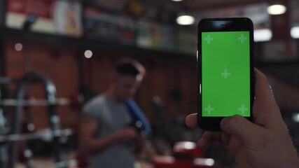 Close up hand man use phone with vertical green screen in in sport club background man touch approve cell touchscreen active gym mobile young application monitor internet device, holding online