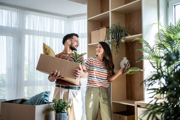 Happy couple arranging belongings in new apartment after moving in