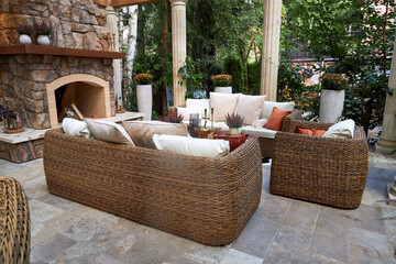 Cozy outdoor terrace with stone fireplace, wicker chairs, and colorful blooming flowers. A stylish garden patio blending rustic charm with natural elegance and relaxing atmosphere