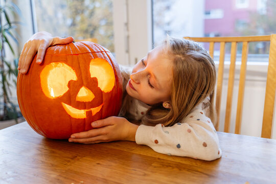 Naklejki Girl enjoying Halloween with carved pumpkin at home