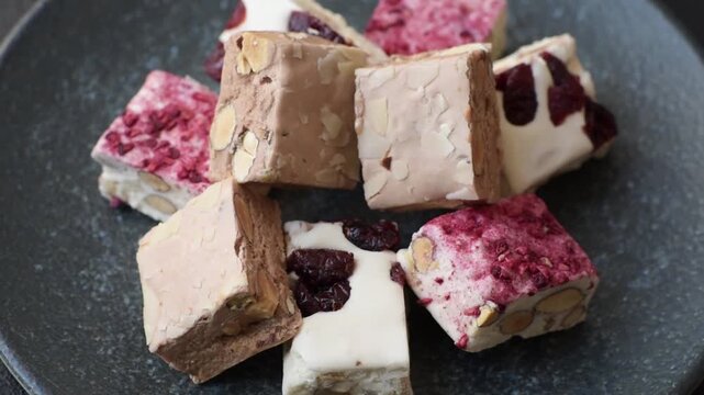 Nougat or white caramel with hazelnuts and pistachios and strawberry pieces. White nougat with nuts, sweets for the festive table
