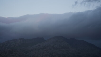 Dark moody scene of mountains covered by low heavy clouds in Cape Town
