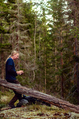 Fototapeta premium Man focused on smart phone in the forest
