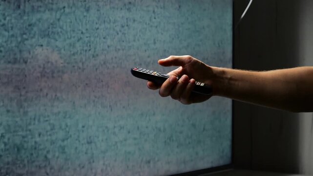 Male hand anf broken TV with white noise on screen.
Close-up of TV static and white noise on screen.
Broken TV and hand with remote control