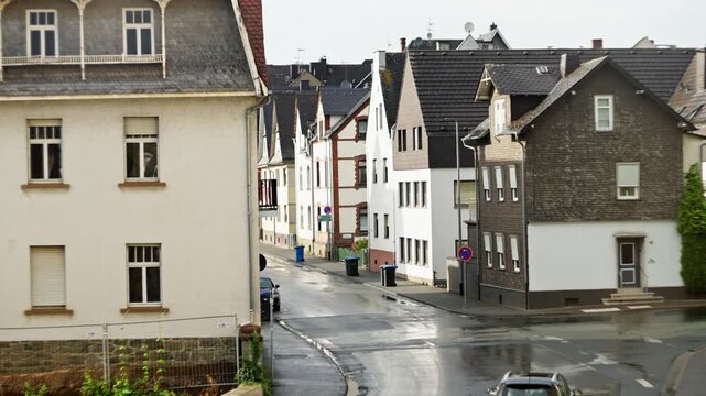 Germany Herborn 16 07 2025. A city street scene showcasing an orange bus navigating through a charming residential neighborhood.