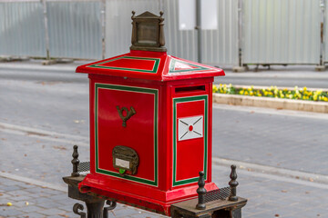 Vintage red metal mailbox with green and white trim standing on street in Budapest old town. Historic post letter box as retro communication symbol and urban detail. Budapest, Hungary
