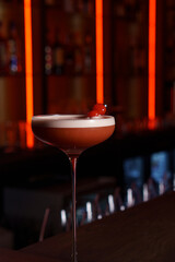 Berry cocktail with foam in a glass in a dark bar