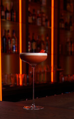 Berry cocktail with foam in a glass in a dark bar
