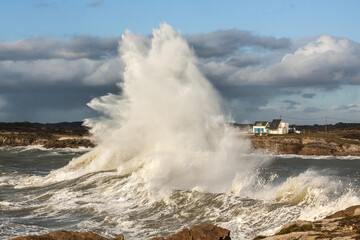 Ploemeur Morbihan Immense storm wave crashing against harbor defenses, spray rising into the sky.