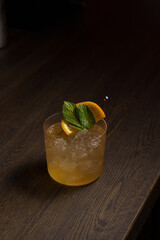 Orange cocktail in a glass goblet in a dark bar
