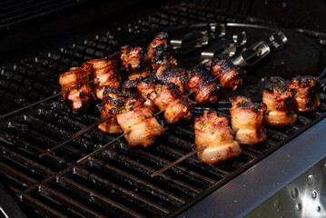 Grilled pork belly skewers cooking on barbecue grill