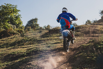 Fototapeta premium Motocross rider climbing a steep hill on a sunny day