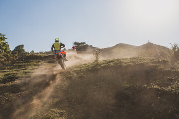 Obraz premium Motocross riders climbing dusty hill in sunny day