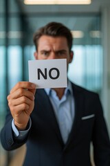 A Man Holding a Card Clearly Displaying the Word 'No,' Symbolizing Rejection and Assertiveness in a Professional Setting