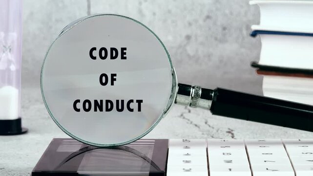 Animation of the CODE OF CONDUCT concept words through a magnifying glass in close-up. Business, Ethics and respect in working collective concept.