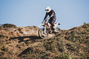 Motocross rider climbing hill on sunny day