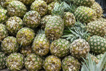 Fresh pineapples stacked in bulk at a market stall.