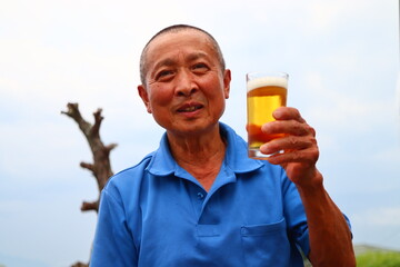 ビール片手に微笑むシニア男性のおじさん