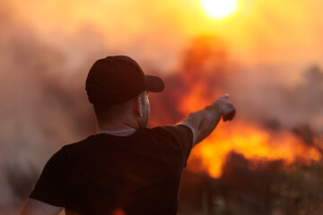 Man Points Towards a Raging Wildfire Under a Smoggy Sun