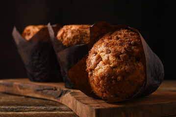 Three fresh baked coffee cake muffins on a cutting board.