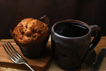 A mug of coffe with fresh baked muffin on a cafe table.