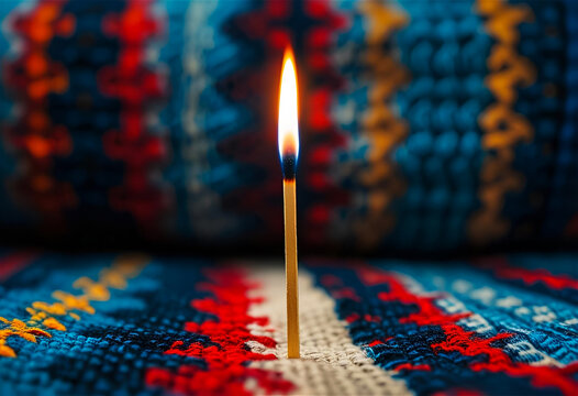 Burning match has blue, red, and yellow colors, textured fabric surface; dramatic lighting for presentations, video background, social media.