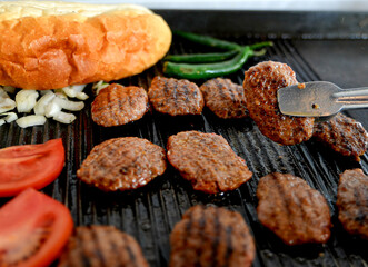 The cook is holding the meatball with tongs
