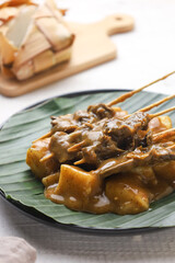 Sate padang. Padang satay made from beef with peanut curry sauce. served with lontong or rice cake. perfect for recipe, article, or any commercial purposes.