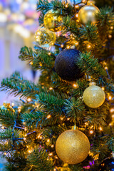 Christmas tree decorated with golden and black glitter baubles, shiny ornaments and glowing fairy lights, festive holiday background with sparkling decorations, close up of New Year celebration