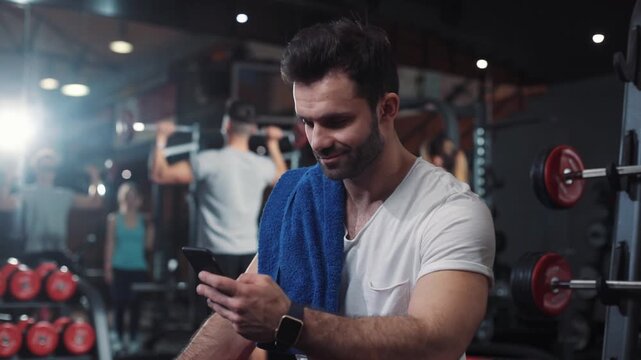Portrait guy in gym while resting between a workout uses phone body strength fit health male strong healthy muscular athlete guy physical young arm model mobile caucasian endurance close up