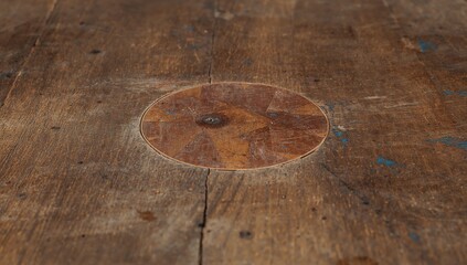 Close up low angle shot of a worn wooden surface with a circular imprint and texture
