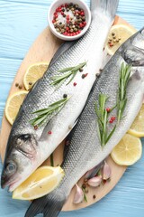 Fresh raw seabass with spices on blue wooden table, top view. Fish and seafood delicacies