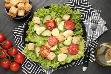 Delicious salad with croutons and ingredients on black table, flat lay