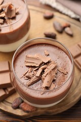 Delicious panna cotta with chocolate and cocoa beans on wooden table, closeup