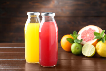 Tasty juices in glass bottles, fresh fruits and mint on wooden table, selective focus
