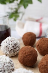 Delicious homemade candies with cocoa powder and coconut flakes on table, closeup