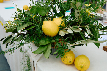 Lemons integrated in green leafy centerpiece on white table